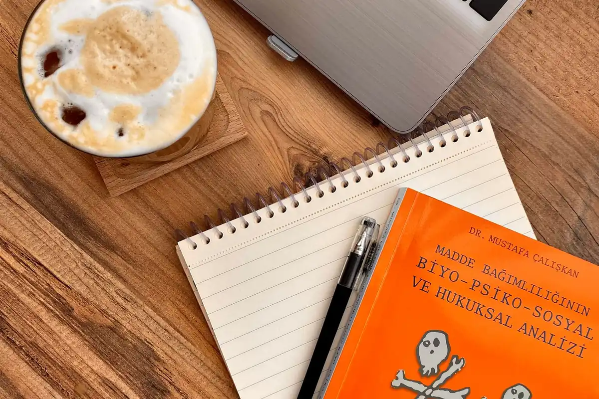 Laptop, notebook, coffee and a book on a wooden desk set up for a job search