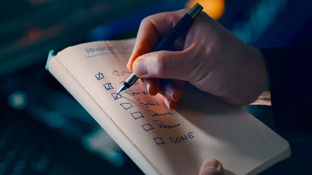 Hand checking off items on a handwritten checklist in a notebook