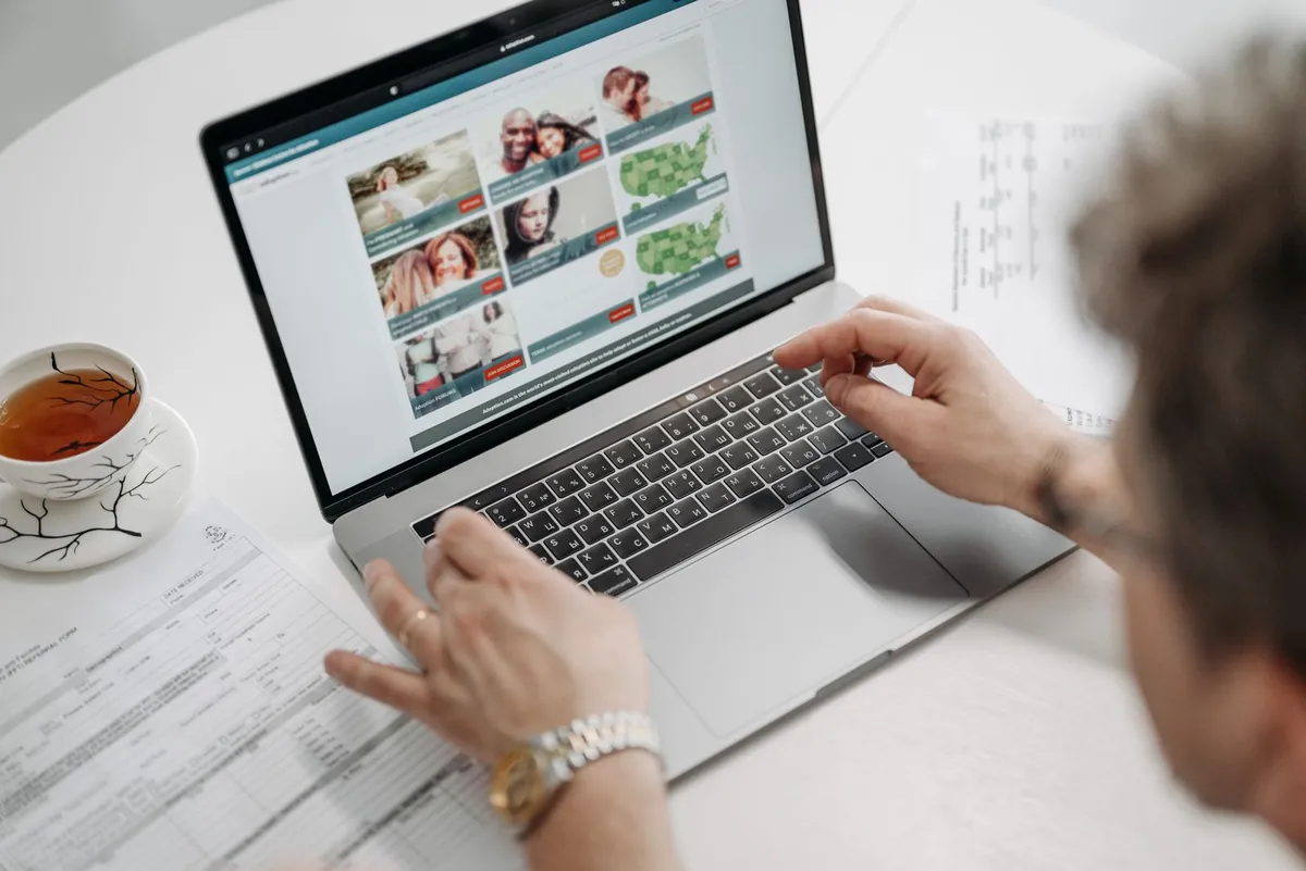 Job seeker browsing a job listings website on a laptop with documents nearby