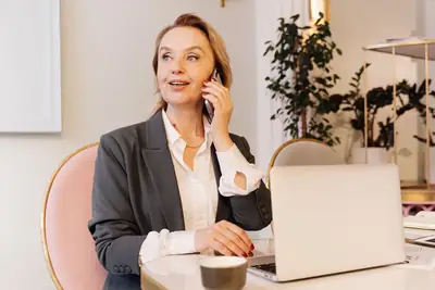 Professional on a phone call at her desk with a laptop open, as in a recruiter screen